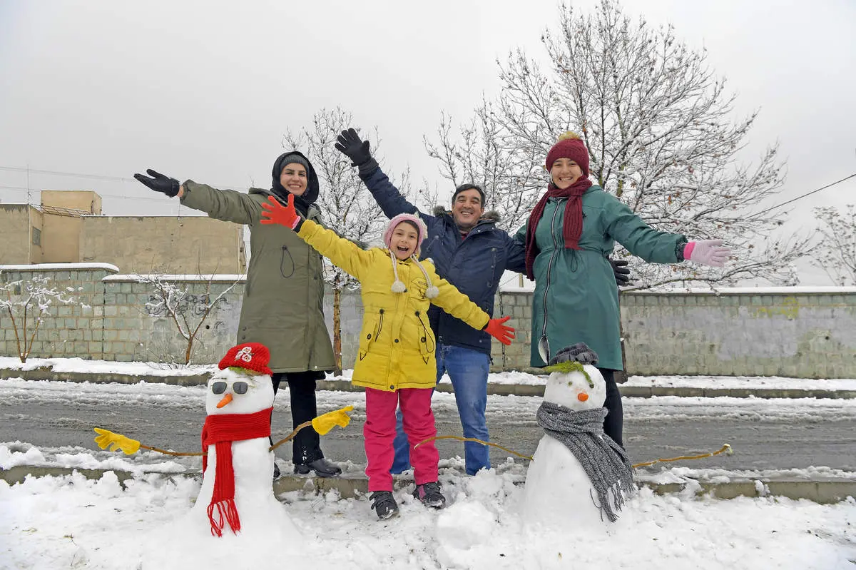 خانواده رنگین کمانی در کنار آدم برفی‌ها/ عکس